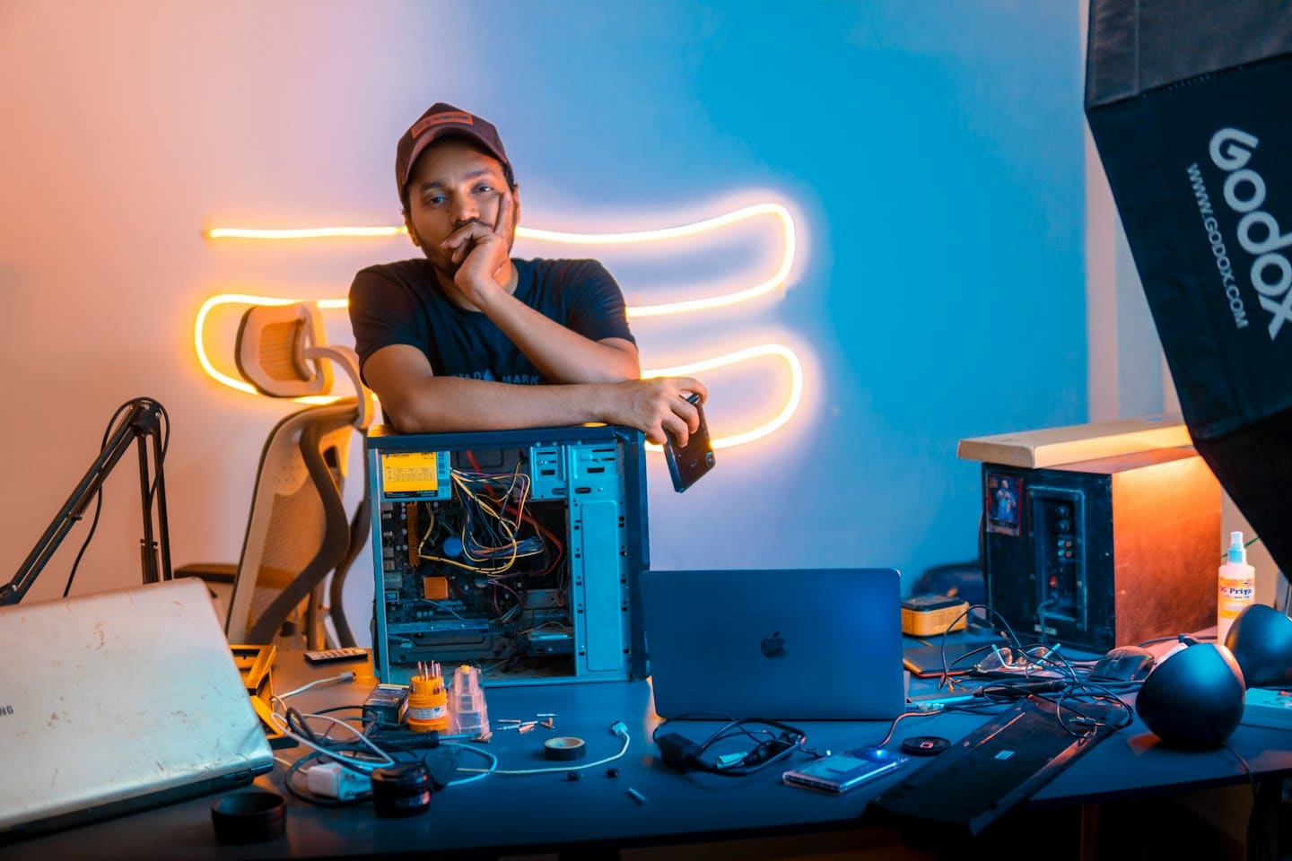 Technician with smartphone examines open computer tower.